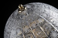 Detalle del tallado en forma de encaje en la pantalla de cristal de una lámpara decorativa.