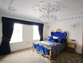La versión de 18 bombillas de la lámpara de araña combina con la cama doble azul del dormitorio.