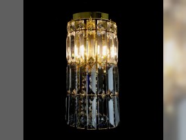 Otra imagen de un aplique más pequeño con prismas y bolas de cristal con acabado dorado —encendido—
