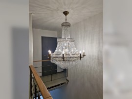 La lámpara de araña encaja perfectamente en un interior minimalista con madera en la barandilla.